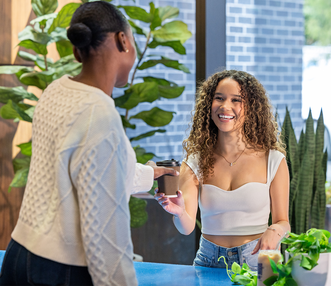 A woman smiling and receiving her coffee